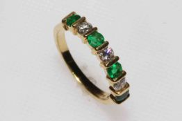 Emerald and diamond half eternity ring set in 18 carat yellow gold, size N.