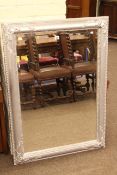 Swept chromed framed bevelled wall mirror, 107cm by 76cm overall.