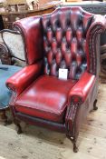 Ox blood deep buttoned leather wing back armchair.