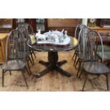 Ercol dark elm circular extending dining table and six swan back chairs.
