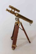 Brass table top telescope raised on wood and brass tripod.