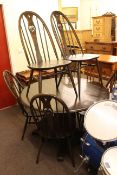 Ercol dark elm circular extending dining table and six swan back chairs.