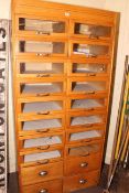 Oak haberdashery cabinet having two banks of eight glass front drawers above,