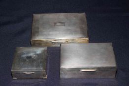 Three silver engine-turned cigarette boxes, the largest one with inscription, 16.5cm across.