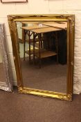 Rectangular gilt swept frame bevelled wall mirror, 106cm by 75.5cm overall.