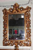 Ornate gilt framed rectangular bevelled wall mirror, 125cm by 79cm overall.