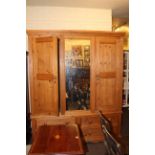 Pine combination wardrobe having central mirror flanked by two panelled doors above four drawers,