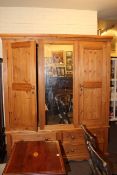 Pine combination wardrobe having central mirror flanked by two panelled doors above four drawers,