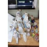Twelve figurines including three Lladro and four Nao together with eleven glass paperweights and