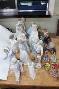 Twelve figurines including three Lladro and four Nao together with eleven glass paperweights and