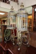 Pair of gilt metal and glazed hall lanterns on ornate stands, 109cm high.