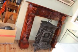 Ornate cast iron stove together with a carved polished mahogany fire surround.