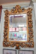 Ornate gilt framed rectangular bevelled wall mirror, 125cm by 79cm overall.