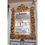 Ornate gilt framed rectangular bevelled wall mirror, 125cm by 79cm overall.