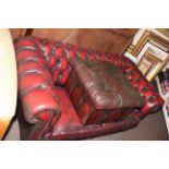 Ox blood deep buttoned leather two seater Chesterfield settee and footstool.