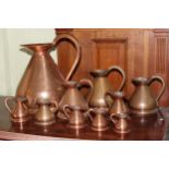 Set of ten graduated copper jugs.