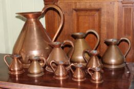 Set of ten graduated copper jugs.