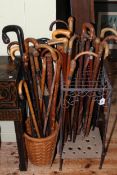 Collection of vintage walking sticks in a stick stand and basket.