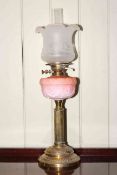 Brass column oil lamp with pink moulded reservoir and frosted and etched glass shade.