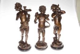 Three bronzed cherubic figures on marble bases, 42cm high.