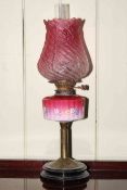 Two brass oil lamps, one with painted pink and red reservoir and ruby glass shade.