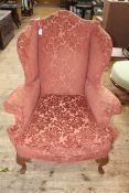Arched back wing armchair on carved cabriole legs.