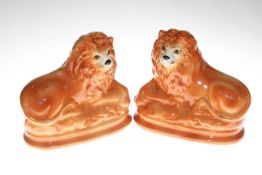 Pair Staffordshire recumbent lions with glass eyes, 26cm wide.