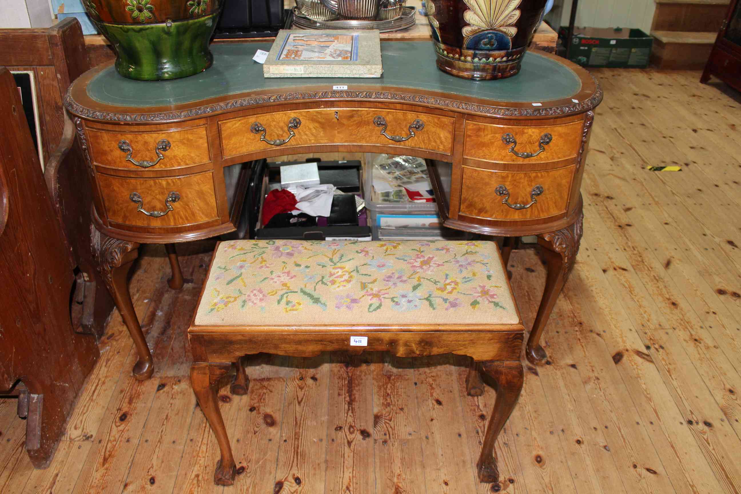 Walnut five drawer kidney shaped writing table 77cm by 126cm together with a floral needlework
