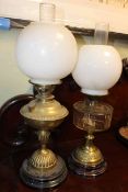 Two brass oil lamps with opaque glass shades.