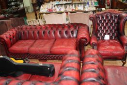 Ox blood deep buttoned leather three seater Chesterfield settee and wing armchair.