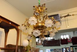 Ornate gilt metal and brass twelve-branch chandelier with leaf and petal design.