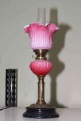 Victorian oil lamp with opaque ruby glass reservoir and fluted shade, 43cm to top of shade.