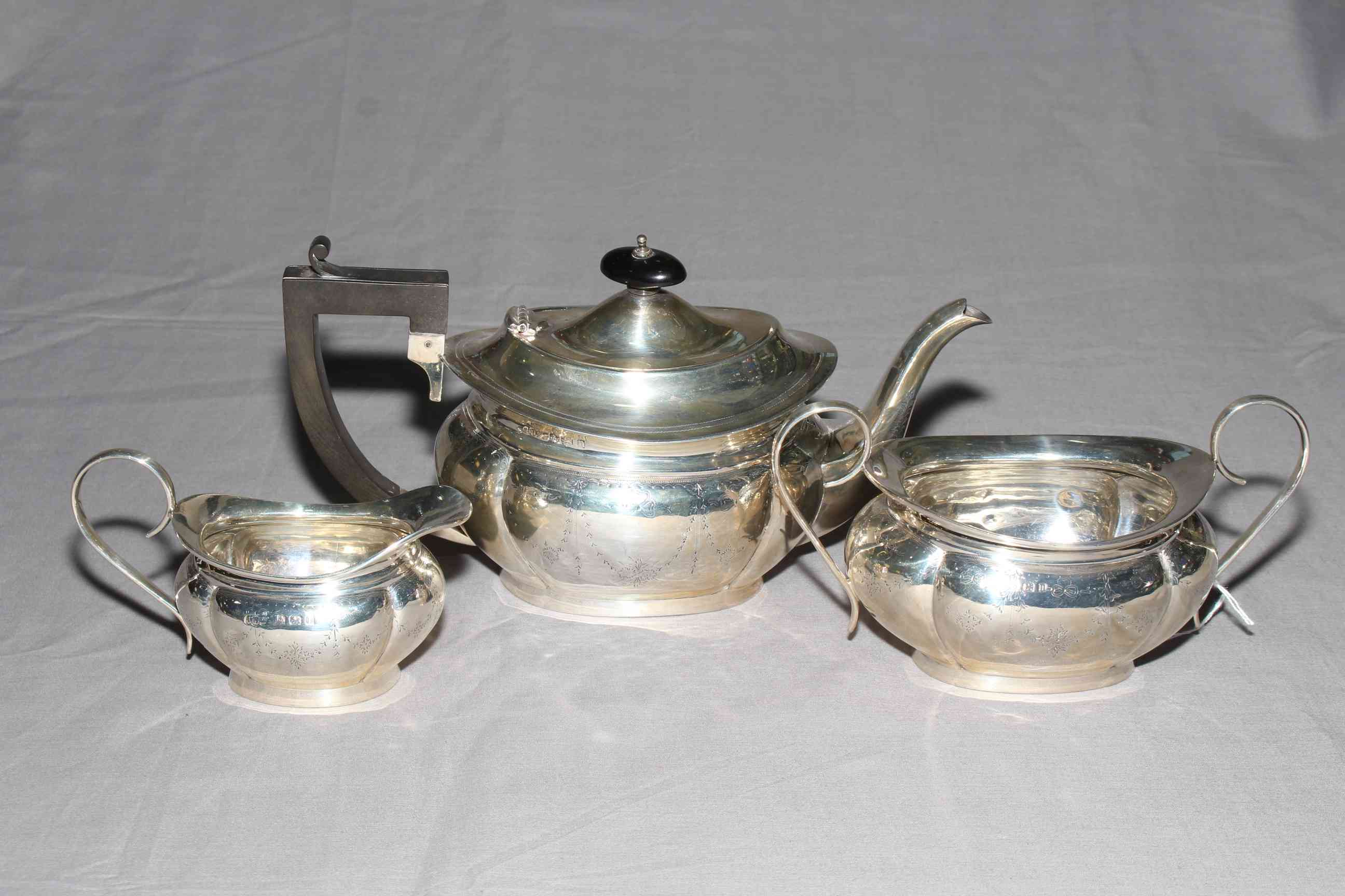Silver three piece tea set of lobed oval form engraved with garland, Birmingham 1911.