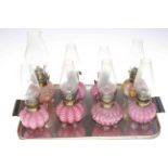 Eight Victorian miniature coloured glass oil lamps with chimneys.