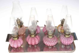 Eight Victorian miniature coloured glass oil lamps with chimneys.