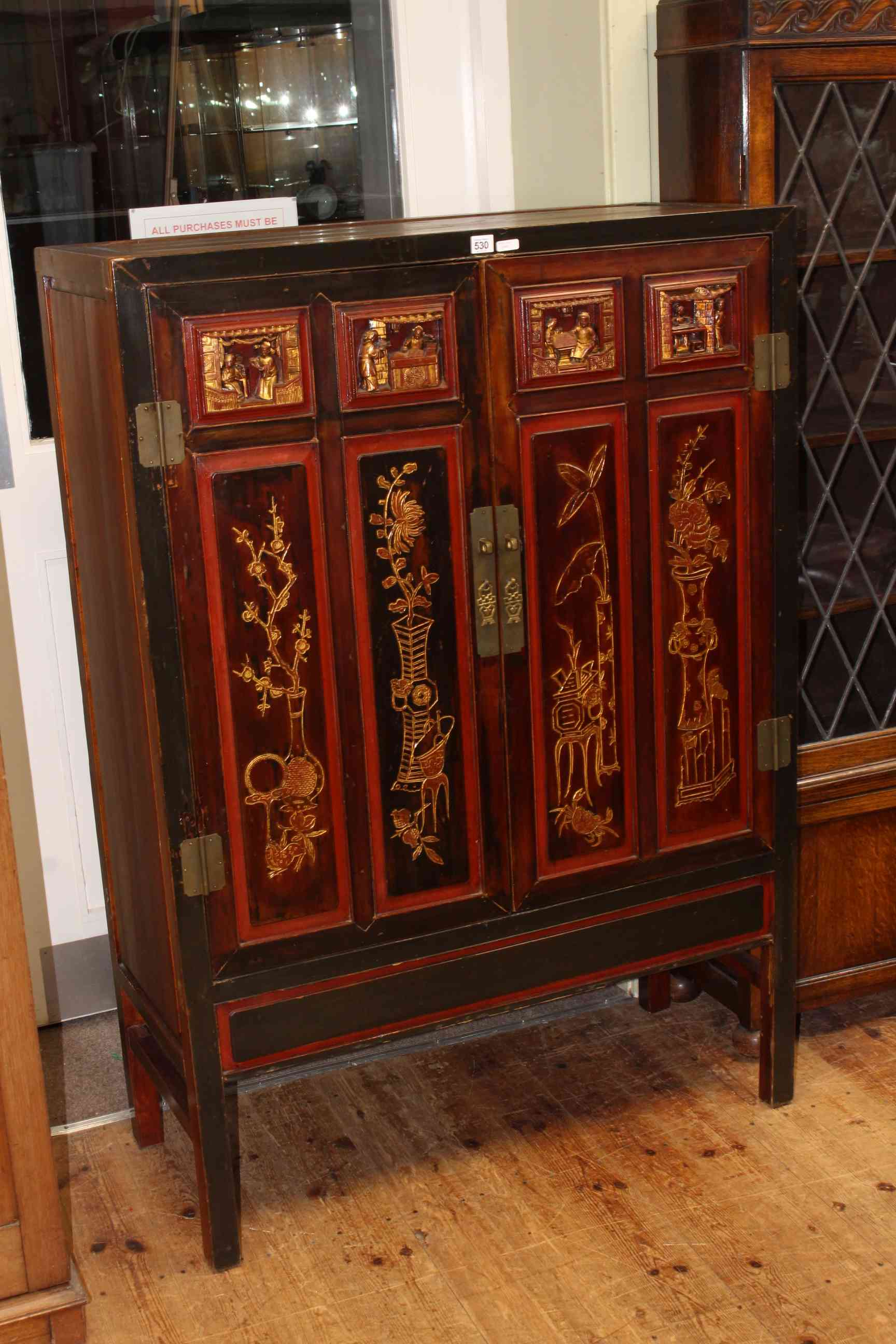 Chinese two door cabinet, the doors with carved relief figure and floral decoration,