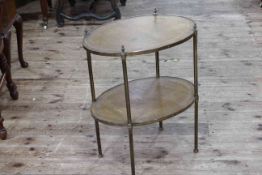 Oval brass and leather inset two tier table, 66cm by 54cm by 39cm.