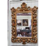Ornate gilt framed bevelled wall mirror, 124cm x 84cm overall.