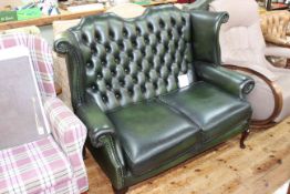 Bottle green buttoned leather wing back two seater settee.