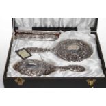 Cased silver embossed four piece brush and mirror set.