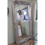 Rectangular ornate silvered framed bevelled wall mirror, 203cm by 102cm.