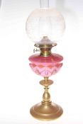 Victorian brass oil lamp with pink decorated glass reservoir and etched and frosted glass shade.