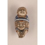 Japanese porcelain netsuke, modelled as a boy on his fathers shoulders, blue enamel, 6.3cm high.