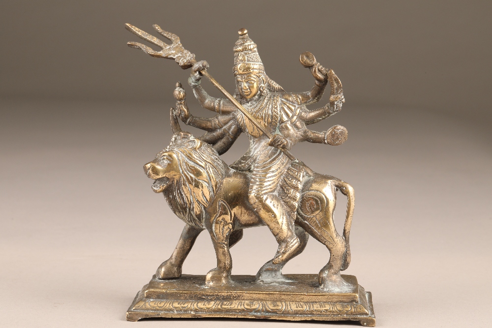 Bronze figure of a Buddhist deity, with eight arms astride a male lion, 14cm long, 17cm high.