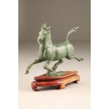 20th century Chinese bronze figure of a horse, green patina raised on a hardwood stand. 35cm long,