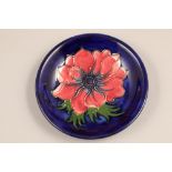 Moorcroft pottery shallow bowl decorated in anemone design, on blue ground, initialled WM and