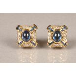 Boxed pair of 18 carat gold earrings, each set with a central blue sapphire cabochon surrounded by