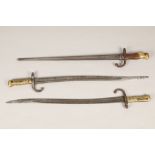 Three assorted French bayonets, two with brass grips without scabbards, and one with wood and