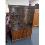 An Edwardian mahogany double door glazed bookcase fitted with cupboards below
