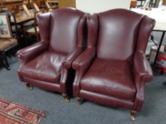 A pair of Victorian style wing backed armchairs upholstered in burgandy leather